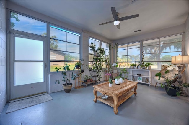 sunroom / solarium featuring finished concrete floors and ceiling fan