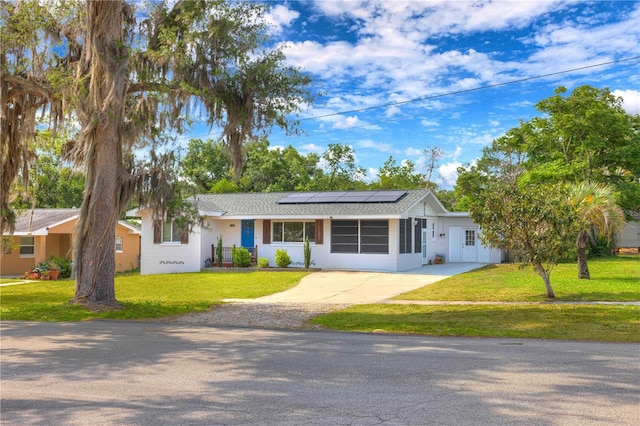 ranch-style house with concrete driveway, solar panels, and a front lawn