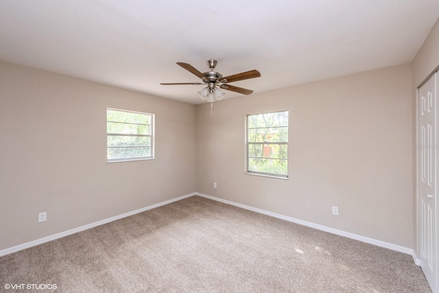 carpeted spare room featuring ceiling fan and baseboards