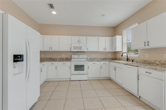 kitchen featuring white appliances, a sink, white cabinetry, light stone countertops, and light tile patterned flooring