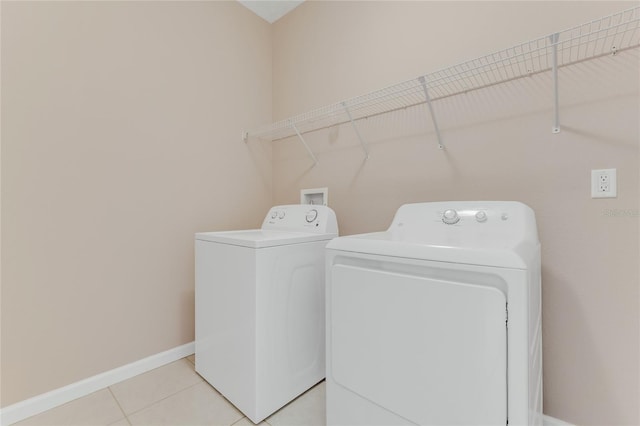laundry room featuring washer and dryer, baseboards, and light tile patterned floors