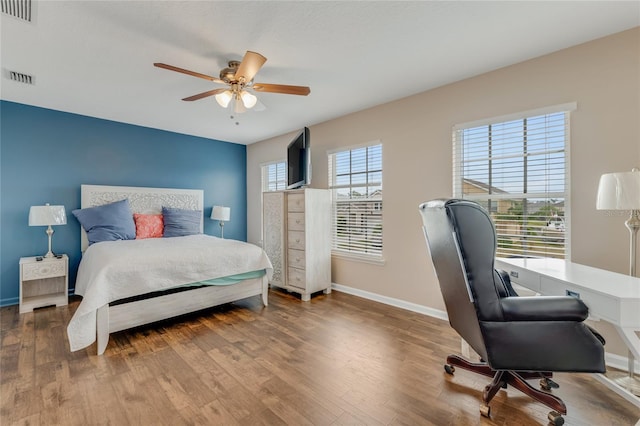 bedroom featuring wood finished floors, baseboards, a ceiling fan, and a desk