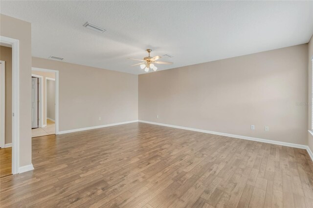 spare room with ceiling fan, light wood-style floors, and baseboards