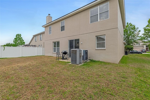 back of property with central AC, a chimney, and stucco siding