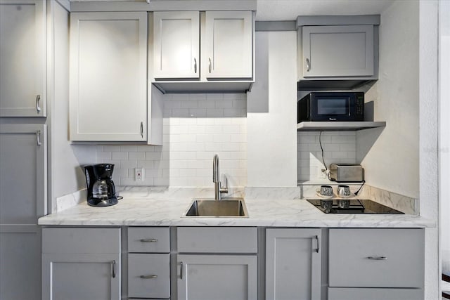 kitchen featuring gray cabinets, a sink, black appliances, and backsplash