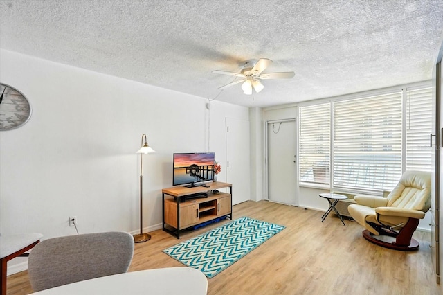 sitting room with light wood finished floors, ceiling fan, and a textured ceiling