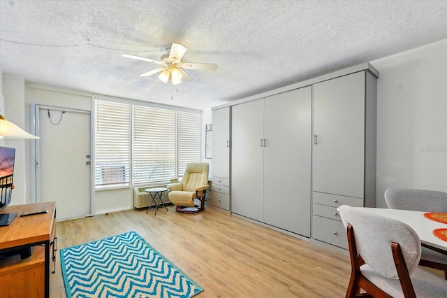 sitting room featuring light wood finished floors, a textured ceiling, and ceiling fan