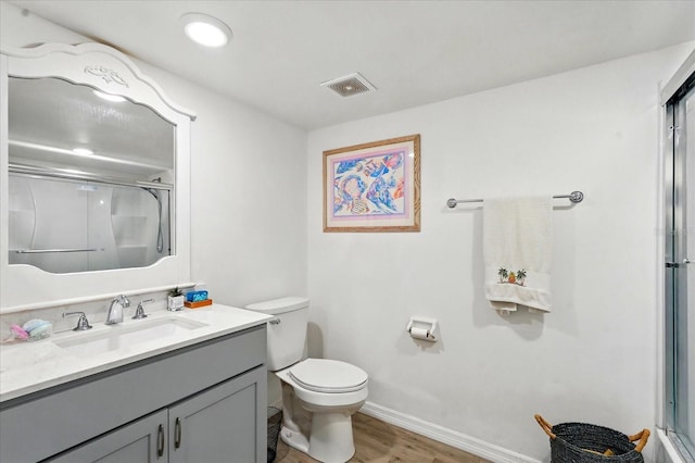 full bath featuring a shower with door, toilet, wood finished floors, vanity, and baseboards