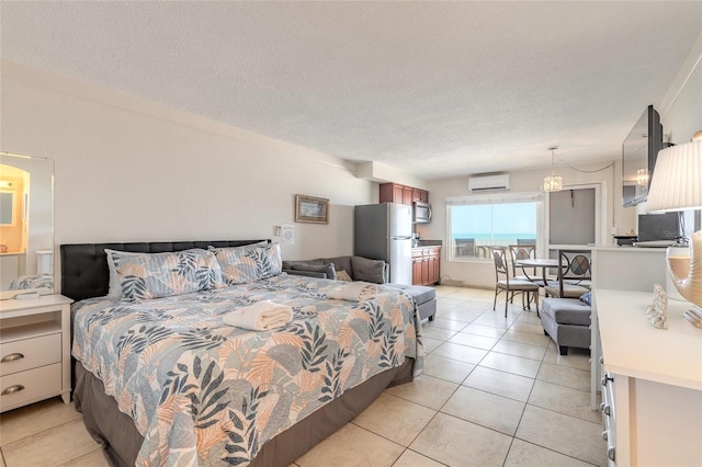 bedroom featuring an AC wall unit, freestanding refrigerator, light tile patterned floors, and a textured ceiling