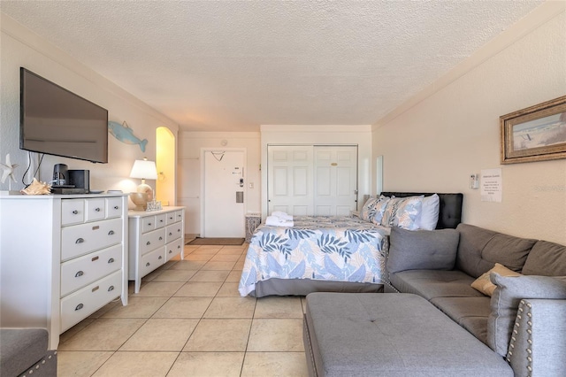 bedroom with light tile patterned flooring, a textured ceiling, and a closet