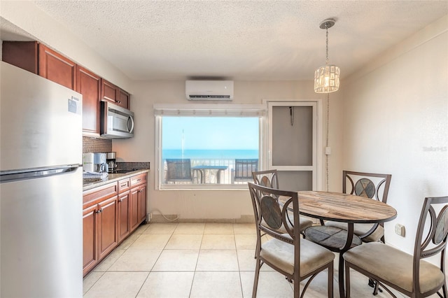 kitchen featuring stainless steel appliances, a wall mounted AC, a chandelier, a textured ceiling, and decorative light fixtures