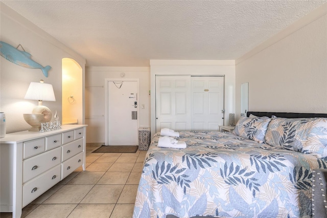 bedroom featuring a closet, light tile patterned floors, and a textured ceiling