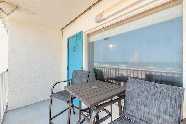 balcony with outdoor dining space and a water view