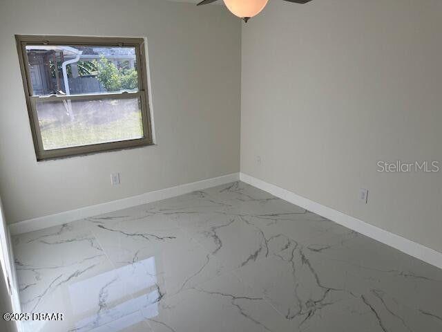 908 Boulder Dr, South Daytona, FL 32119 - spare room featuring baseboards, marble finish flooring, and ceiling fan