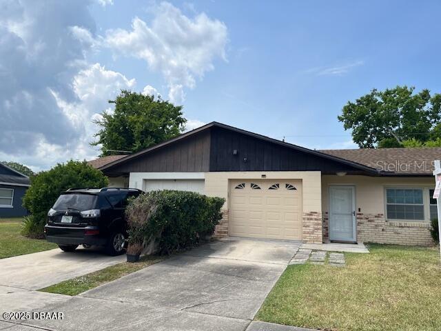 908 Boulder Dr, South Daytona, FL 32119 - ranch-style home with brick siding, a garage, concrete driveway, and a front lawn