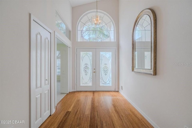 3601 Galway Ln, Ormond Beach, FL 32174 - entryway with french doors, wood finished floors, a chandelier, a towering ceiling, and baseboards