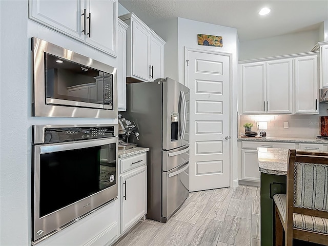 409 Nowell Loop, Deland, FL 32724 - kitchen featuring appliances with stainless steel finishes, white cabinets, light stone counters, and recessed lighting