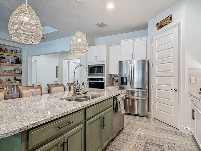 409 Nowell Loop, Deland, FL 32724 - kitchen featuring a sink, stainless steel appliances, green cabinets, white cabinets, and light stone countertops