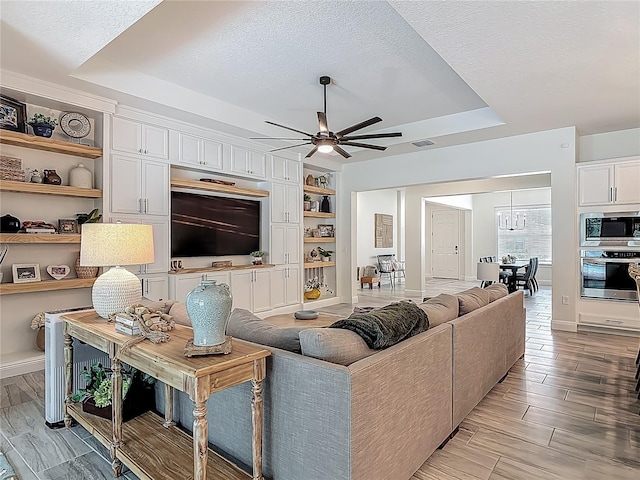 409 Nowell Loop, Deland, FL 32724 - living area with a raised ceiling, a ceiling fan, baseboards, a textured ceiling, and built in shelves