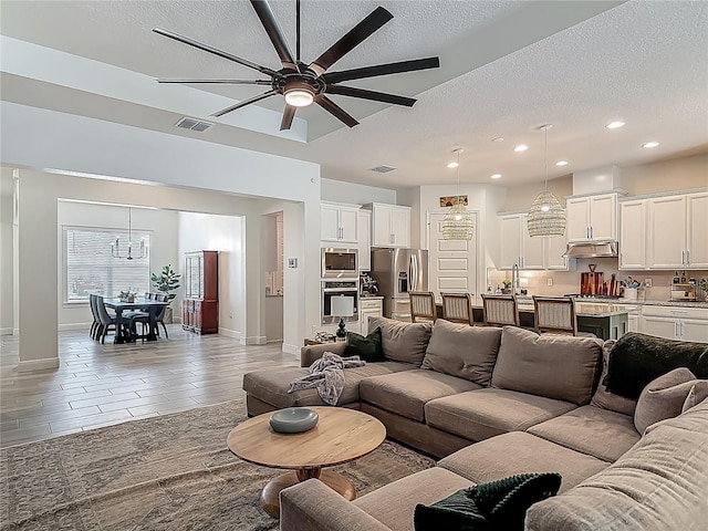 409 Nowell Loop, Deland, FL 32724 - living area featuring a ceiling fan, a textured ceiling, recessed lighting, a chandelier, and baseboards