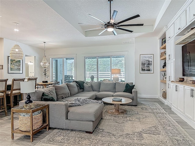 409 Nowell Loop, Deland, FL 32724 - living room with a textured ceiling, ceiling fan, light wood-type flooring, baseboards, and built in shelves