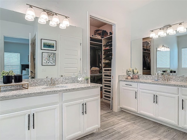 409 Nowell Loop, Deland, FL 32724 - bathroom with two vanities, a walk in closet, and wood finished floors