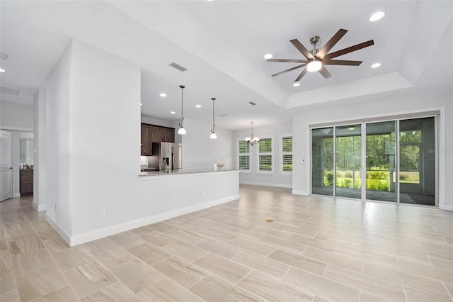 3322 Modena Way, New Smyrna Beach, FL 32168 - unfurnished living room featuring a ceiling fan, a tray ceiling, recessed lighting, baseboards, and a chandelier