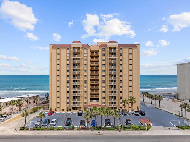 view of apartment building / complex with view of water and beach
