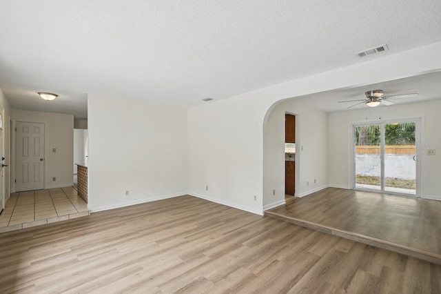 1209 James Ter, Daytona Beach, FL 32117 - unfurnished living room with light wood-style flooring, arched walkways, ceiling fan, baseboards, and a textured ceiling