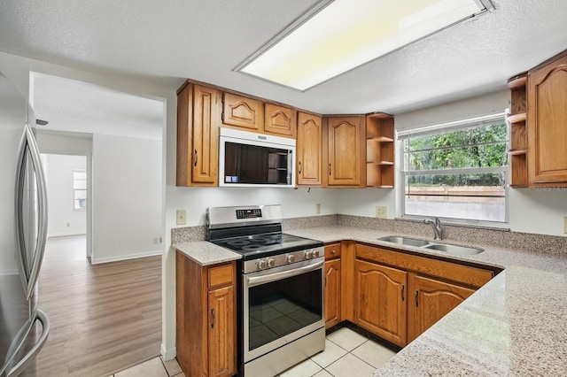 1209 James Ter, Daytona Beach, FL 32117 - kitchen with appliances with stainless steel finishes, a sink, open shelves, brown cabinets, and a textured ceiling