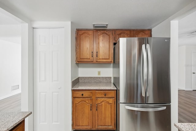 1209 James Ter, Daytona Beach, FL 32117 - kitchen with freestanding refrigerator, brown cabinetry, light countertops, and light wood-style flooring