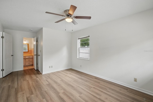 1209 James Ter, Daytona Beach, FL 32117 - unfurnished bedroom with light wood-style floors, baseboards, ensuite bath, and a textured ceiling
