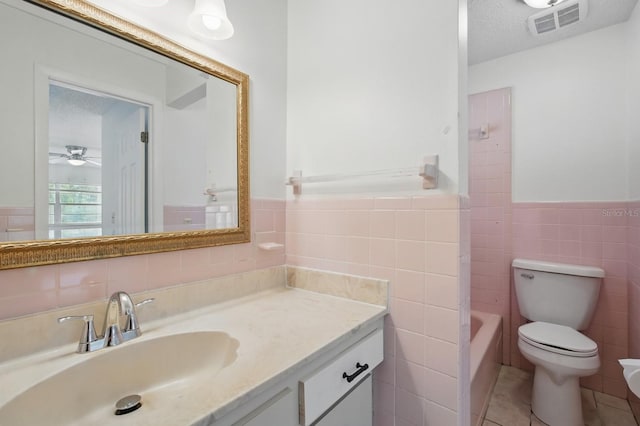 1209 James Ter, Daytona Beach, FL 32117 - full bathroom with tile walls, toilet, vanity, tile patterned floors, and a wainscoted wall