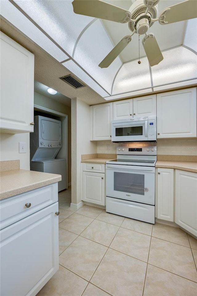 818 Sugar House Blvd, Port Orange, FL 32129 - kitchen with white appliances, estacked washer and dryer, light tile patterned floors, and light countertops