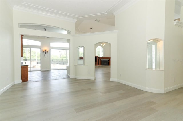 340 Hampton Hills Ct, Debary, FL 32713 - empty room featuring arched walkways, crown molding, light wood-style flooring, a fireplace, and baseboards