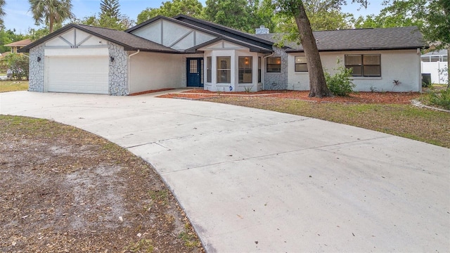 tudor house with stucco siding, concrete driveway, an attached garage, and stone siding