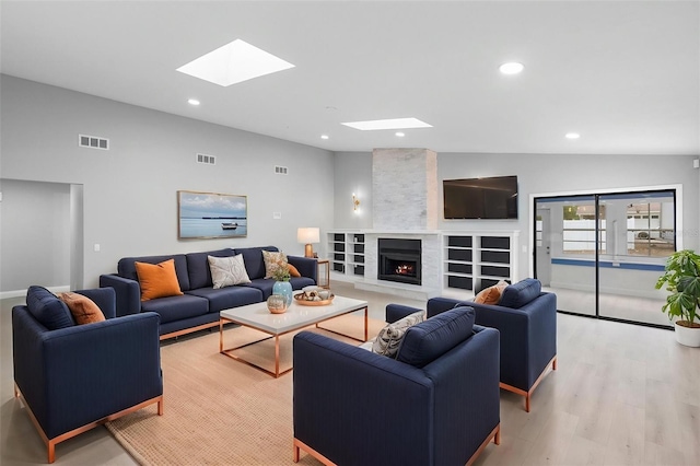 living area with a skylight, a fireplace, light wood-style floors, and recessed lighting
