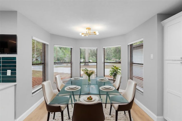 dining space featuring light wood finished floors, a chandelier, and baseboards