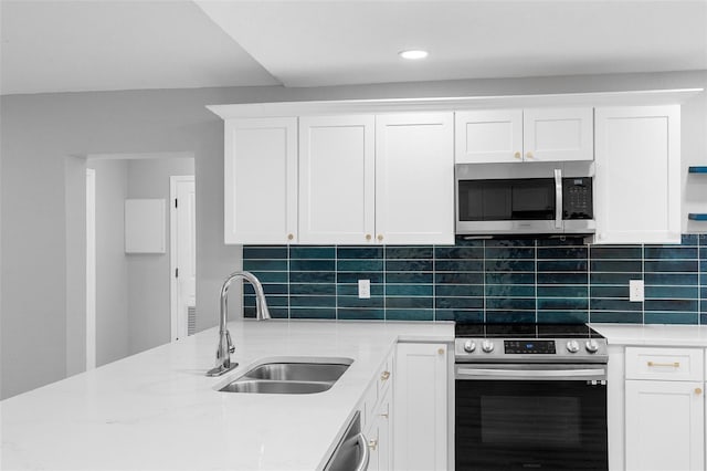 kitchen featuring stainless steel appliances, a sink, white cabinets, tasteful backsplash, and light stone counters