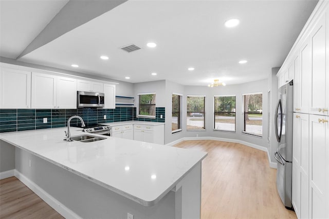 kitchen featuring appliances with stainless steel finishes, a sink, baseboards, a peninsula, and recessed lighting