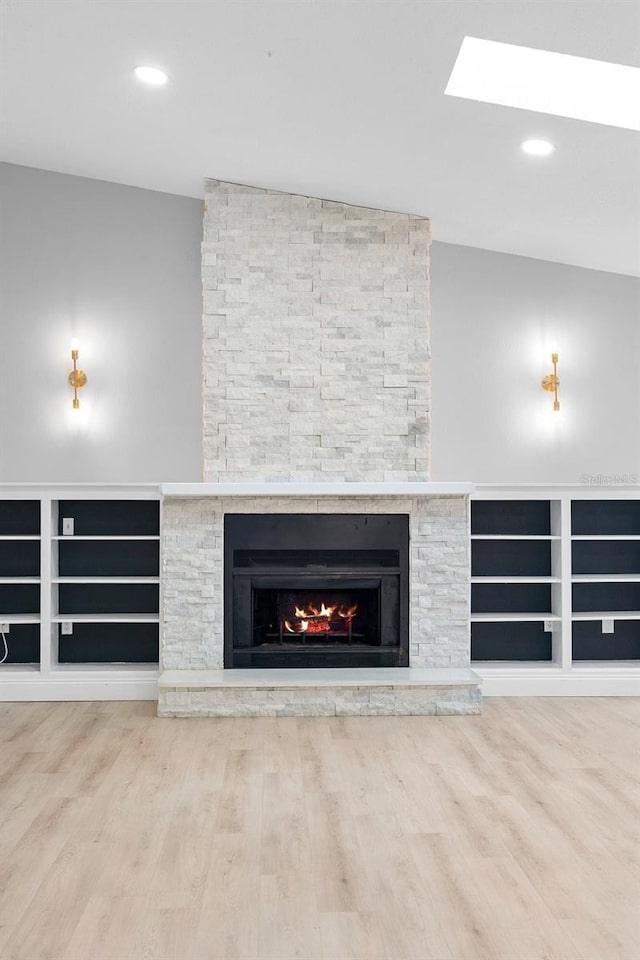 unfurnished living room featuring a stone fireplace, wood finished floors, and recessed lighting