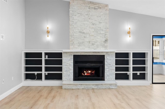 unfurnished living room featuring wood finished floors, vaulted ceiling, a fireplace, and baseboards