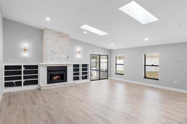 unfurnished living room with a skylight, vaulted ceiling, wood finished floors, a fireplace, and recessed lighting