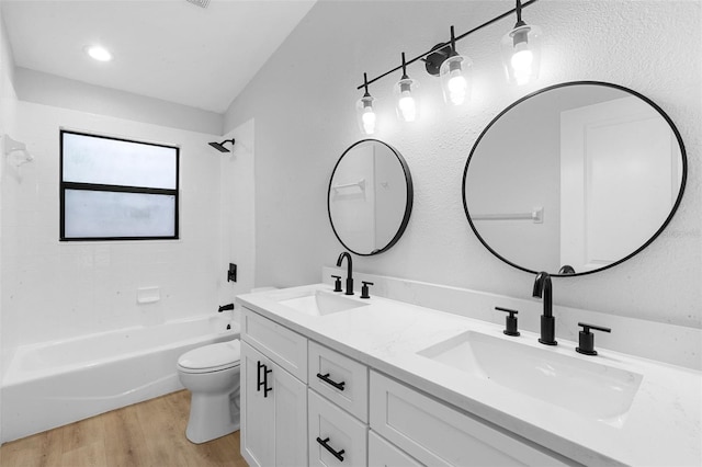 full bathroom with wood finished floors, toilet, shower / washtub combination, and double vanity