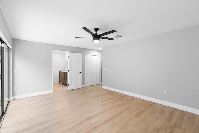 unfurnished bedroom featuring baseboards, light wood-style floors, ensuite bathroom, and ceiling fan