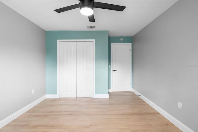 unfurnished bedroom featuring a closet, light wood-style flooring, baseboards, and a ceiling fan