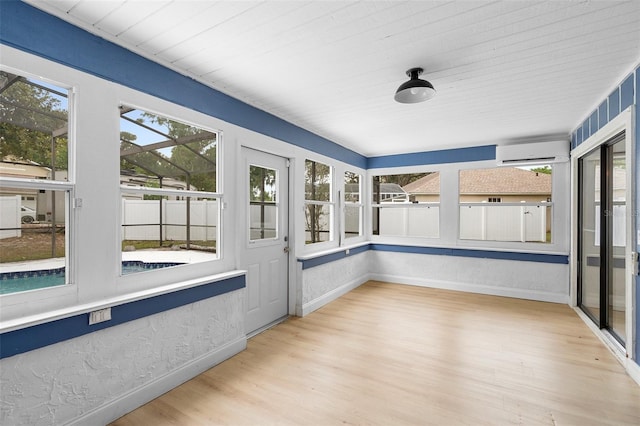unfurnished sunroom with a wall unit AC, baseboards, healthy amount of natural light, and wood ceiling