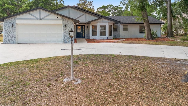view of front of property with concrete driveway, an attached garage, stone siding, and stucco siding