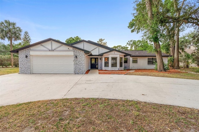 view of front of property with concrete driveway, an attached garage, stone siding, and stucco siding