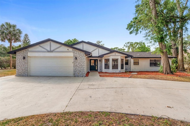 view of front of property featuring driveway, a garage, stone siding, and stucco siding